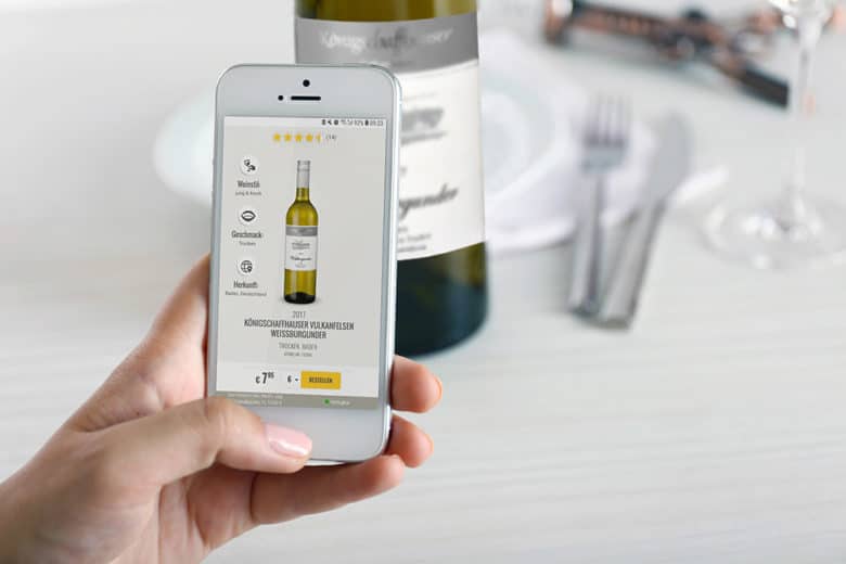 Ein Smartphone wird vor ein Weinetikett gehalten. Über die nfc Technologie wird auf das Smartphone Informationen zu dem Wein übertragen