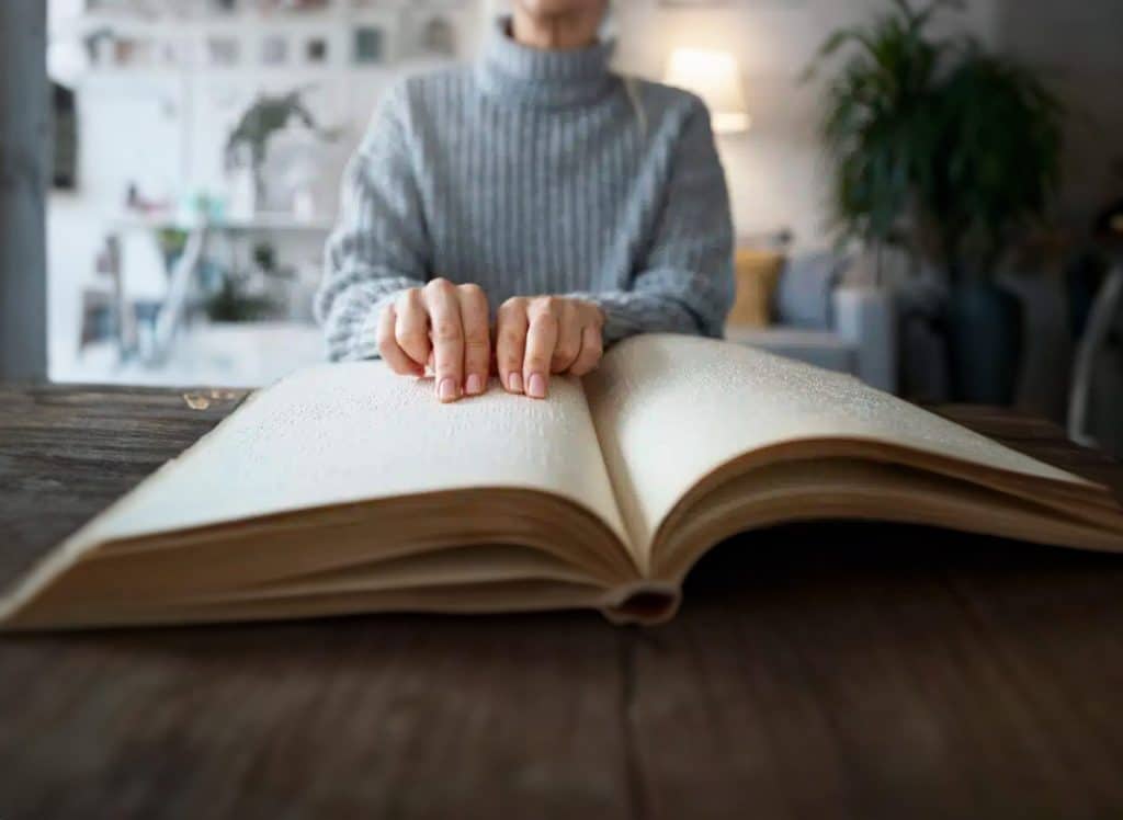 Eine Frau nutzt die barrierefreien Lösungen der ABT Mediengruppe und liest einen Buch in Brailleschrift.