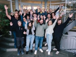 Das ABT Team steht jubelnd zum Teamfoto im Treppenhaus der ABT Mediengruppe.