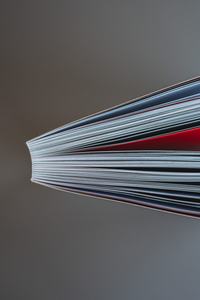 Softcover-Buch mit offener roter Fadenbindung, grauem Kartonumschlag und gedrucktem Innenteil auf Naturpapier