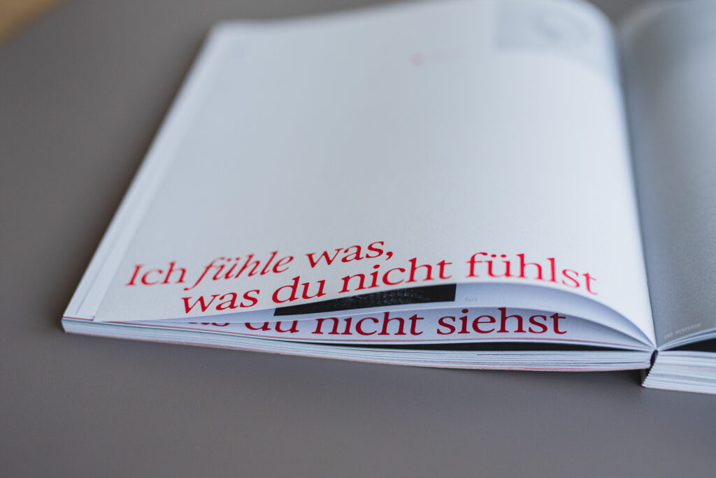 Softcover-Buch mit offener roter Fadenbindung, grauem Kartonumschlag und gedrucktem Innenteil auf Naturpapier