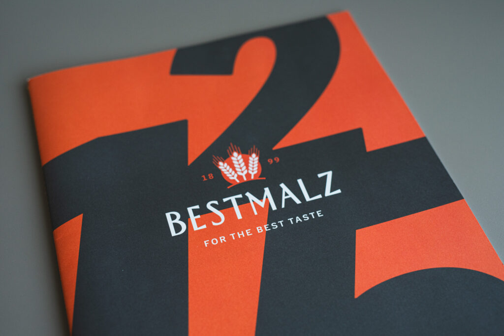 DIN A3 Broschüre auf Naturpapier mit goldgelber Fadenheftung, offen liegend, Detailansicht Bindung und Umschlag