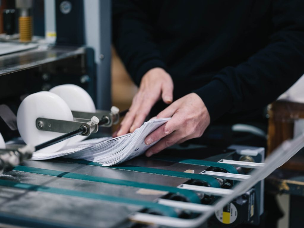 Druckproduktion, Mitarbeiterin an einer Weiterverarbeitungsmaschine