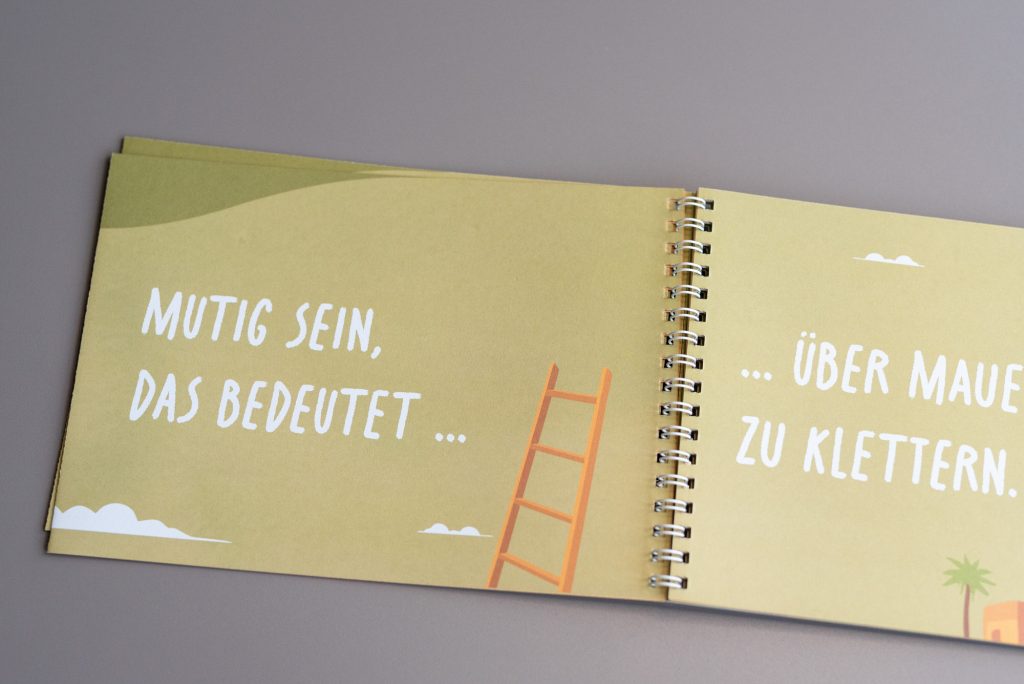 Individuelles Mitmachbuch mit Spiralbindung auf FSC-Recyclingpapier und integrierten Perforationen für interaktive Inhalte.